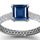 An audacious De Beers ring has a princess center stone on a wide baguette-cut diamond band